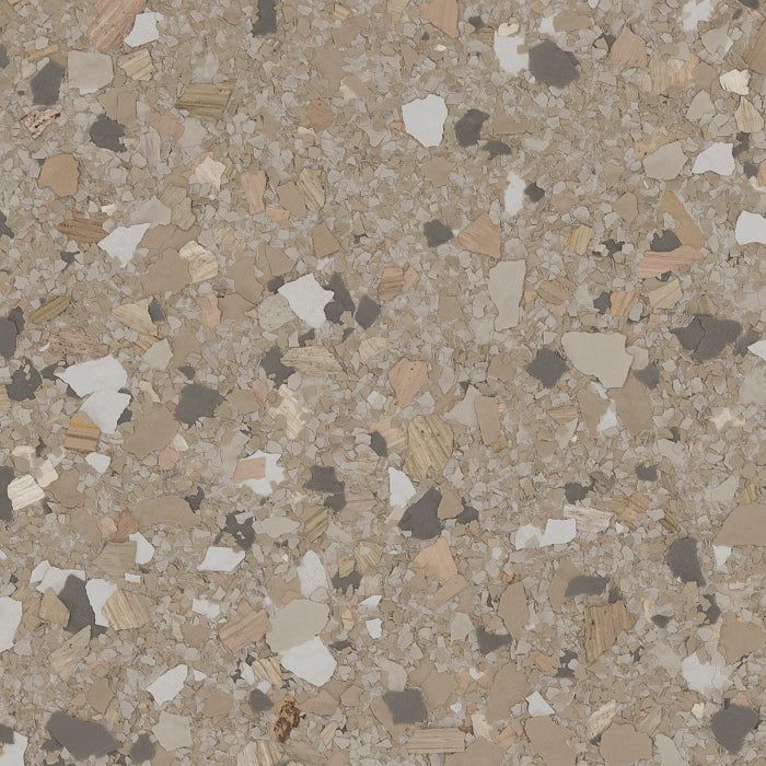 A textured surface with a speckled, multi-colored pattern of tan, brown, white, and dark gray chips.