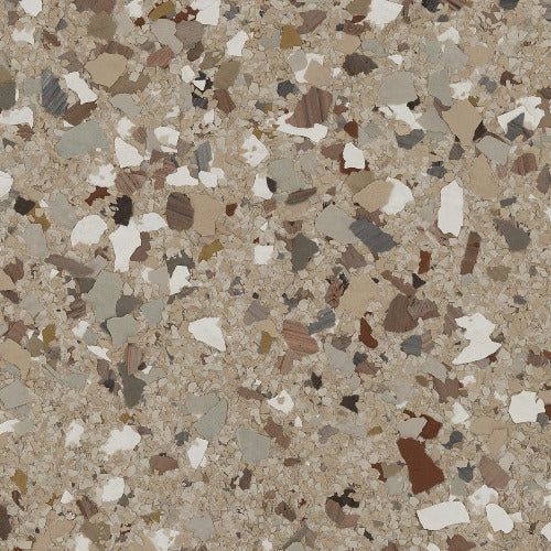 A close-up of tan epoxy flooring with scattered, multicolored paint chips in shades of white, gray, and brown.