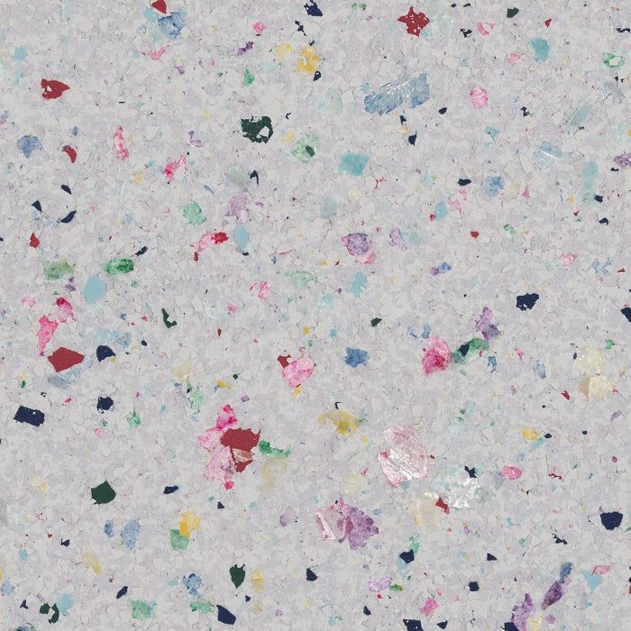 A light grey surface speckled with small, scattered flakes in various colors, including pink, blue, yellow, and green.