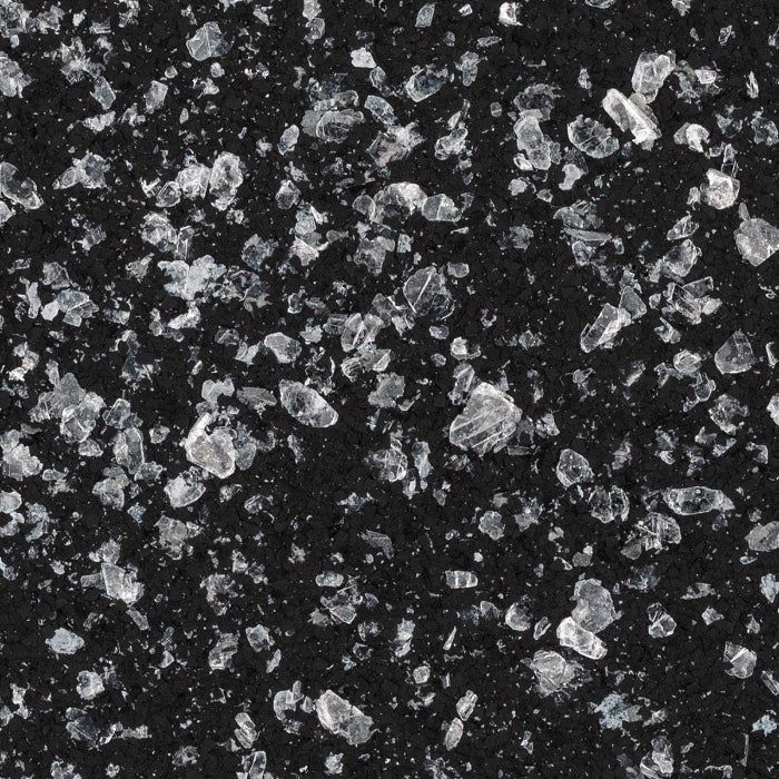 A close-up of a black, textured surface embedded with scattered, jagged pieces of clear, sparkling crystals or minerals.