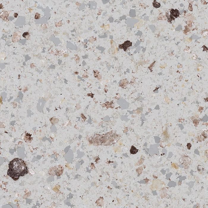 A speckled floor surface with grey, brown, and white flecks on a light grey background, resembling granite or terrazzo.