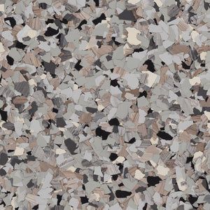A close-up view of epoxy flooring material with a multi-colored flake blend of gray, black, white, and tan chips.