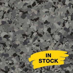 A close-up of grey, black, and white epoxy floor flakes with a yellow 