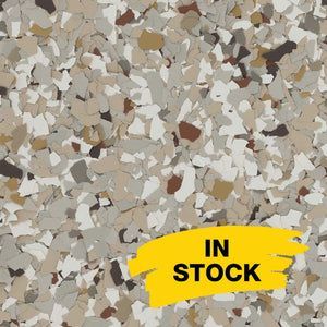 Close-up of decorative paint chips in shades of tan, brown, white, and grey, with a yellow 