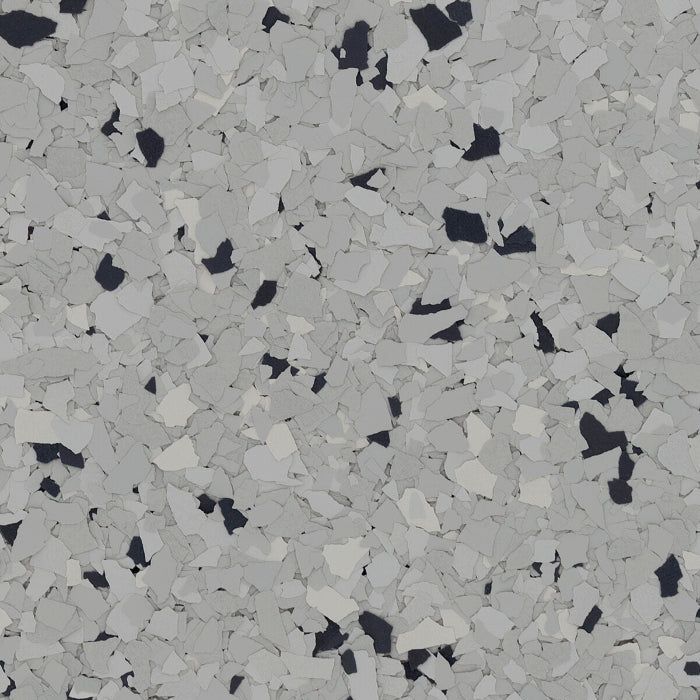 Close-up texture of decorative epoxy flooring with a mix of grey, light grey, and black vinyl flakes.