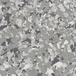 A close-up of grey, white, and black decorative vinyl flakes used for epoxy flooring or countertop finishes.