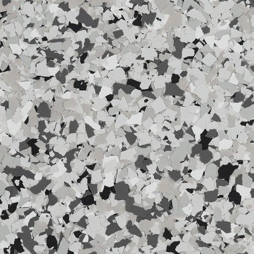 A close-up of a decorative epoxy floor coating with a speckled pattern of black, white, and various shades of grey flakes.
