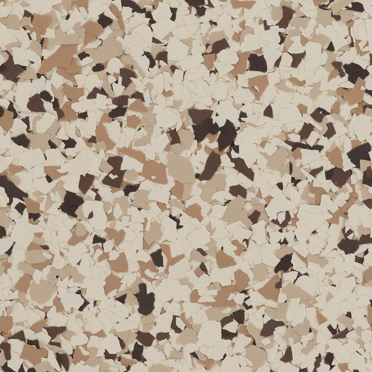 A close-up of decorative epoxy floor flakes in shades of cream, tan, and dark brown.