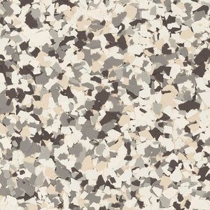 A close-up of a decorative flooring pattern featuring a speckled mix of cream, light gray, and dark brown paint flakes.