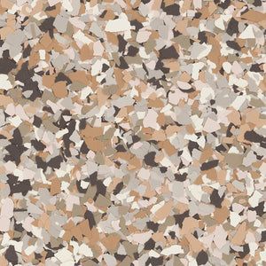 A close-up of decorative epoxy floor flakes in a blend of tan, cream, grey, and dark brown fragments.