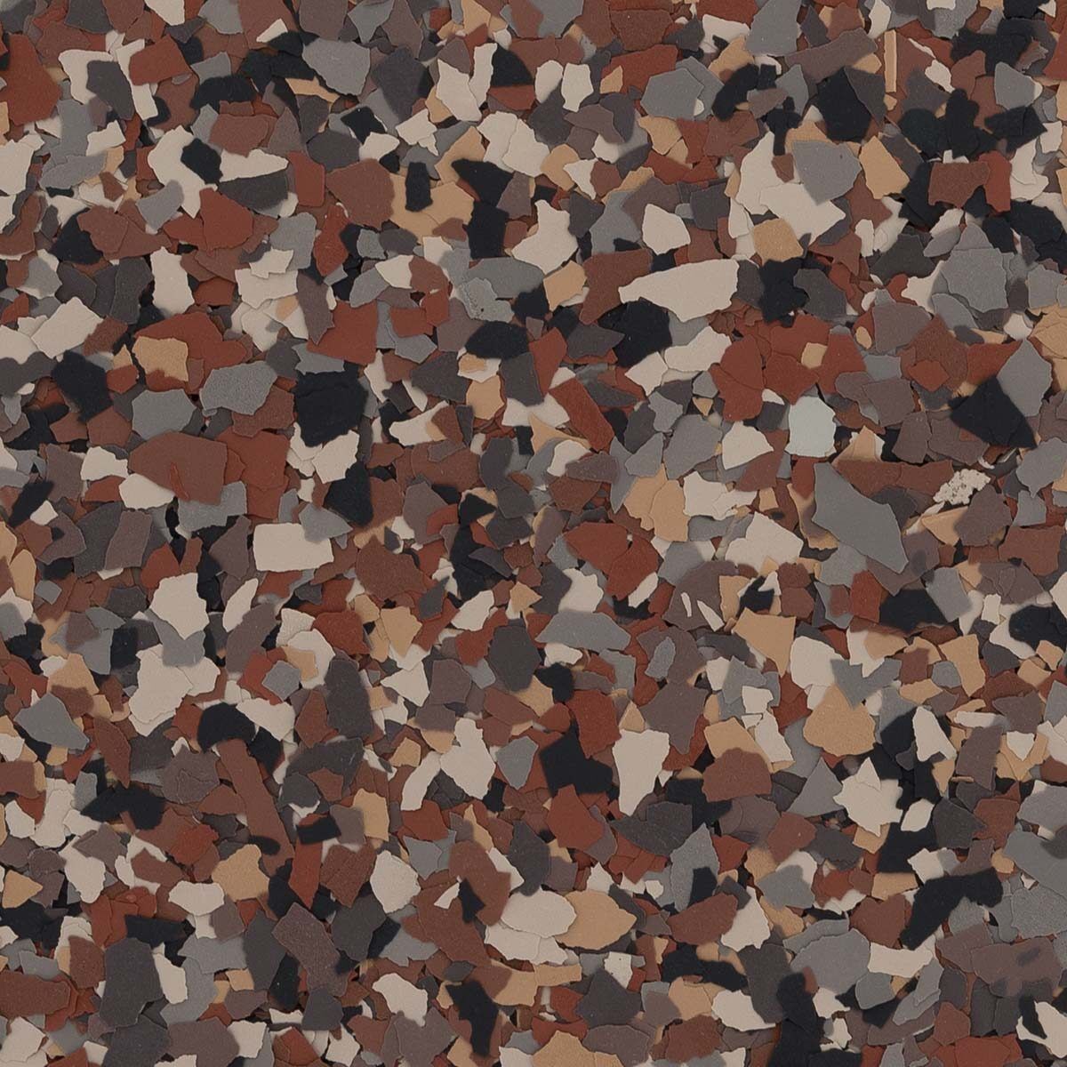 A textured surface of vinyl color flakes in a mix of terracotta, tan, gray, and black, typical of epoxy floor coatings.