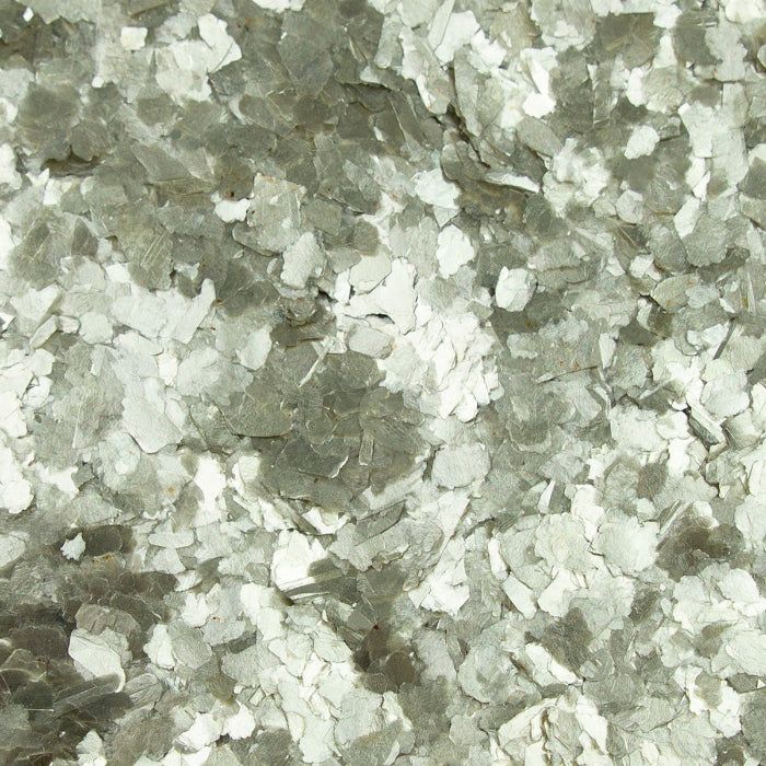 A close-up of decorative gray and white vinyl paint chips used for garage floor coatings.