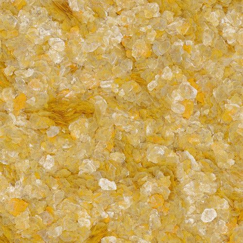 A close-up, top-down view of yellow corn grits, featuring a mix of translucent, crystalline grains and flat yellow flakes.