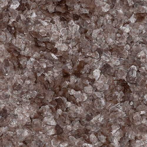 A close-up texture of coarse, dark-brown mineral or salt crystals with uneven shapes and glossy surfaces.