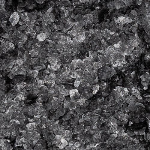 A close-up, high-contrast view of a textured surface composed of small, irregular dark grey and black rock fragments.