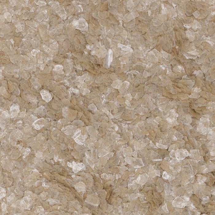 A close-up texture of coarse, light brown grains resembling raw sugar or salt crystals.