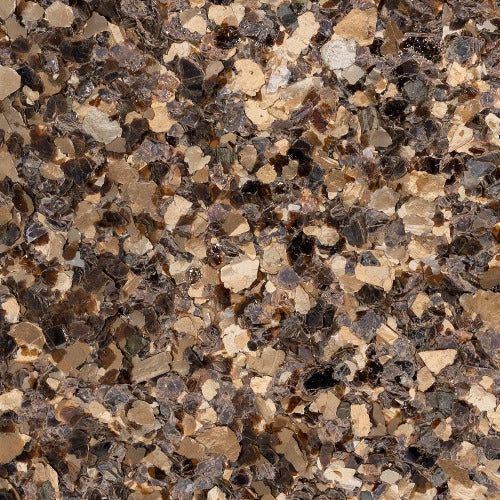 A close-up texture of decorative epoxy flooring flakes in shades of metallic gold, beige, and dark brown.