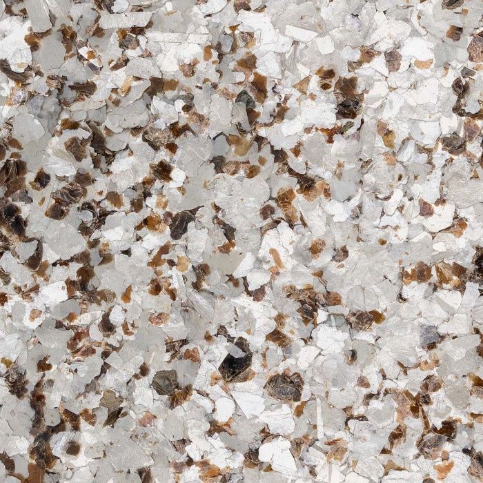 A close-up texture of decorative vinyl floor flakes in shades of white, gray, and dark brown.