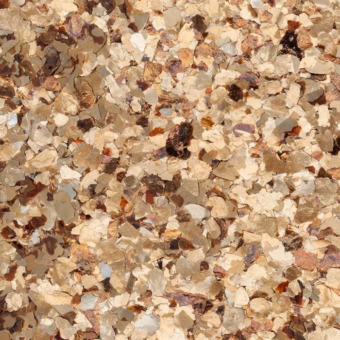 A close-up texture of paint flakes in shades of beige, tan, and dark brown.