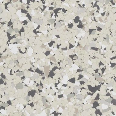 A close-up of a decorative flooring finish featuring a blend of white, beige, grey, and charcoal paint flakes.