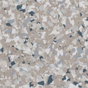 A close-up view of beige, white, grey, and dark blue paint fleck chips commonly used for epoxy flooring surfaces.