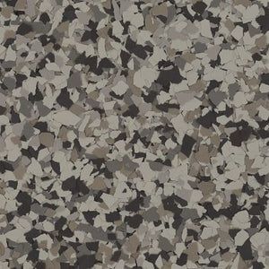 A textured floor surface covered in a speckled pattern of black, white, and various shades of grey flakes.