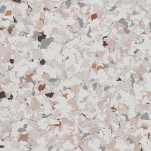 A close-up view of epoxy flooring material featuring a dense, speckled pattern of white, light gray, and tan flakes.