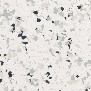 A white surface with a scattered, multi-sized pattern of black, charcoal, and light gray vinyl floor flakes.