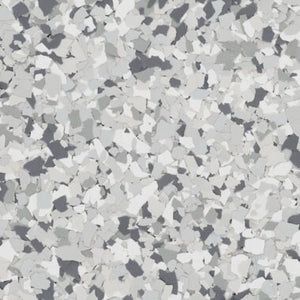 A close-up of speckled floor coating featuring various shades of gray, white, and dark charcoal vinyl flakes.