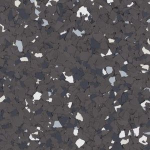 A close-up texture of dark grey, light grey, and white paint flakes scattered on a solid grey surface.