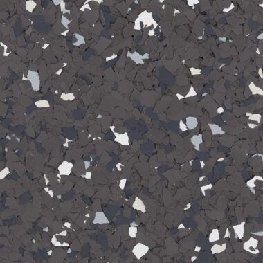 A textured floor surface covered in a mix of dark gray, black, white, and light gray decorative vinyl chips.