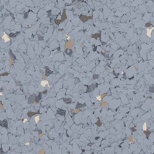 A close-up of light gray epoxy garage floor coating with scattered blue, white, and tan decorative flakes.