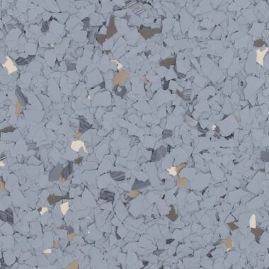 A close-up of light blue, grey, white, and tan decorative paint chips used for epoxy floor coatings.