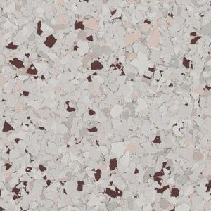 A close-up of a decorative epoxy floor coating featuring a mix of white, light gray, and dark brown flakes.