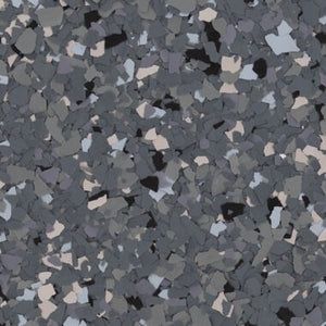 A decorative concrete floor coating with a speckled pattern of black, white, and various shades of gray vinyl flakes.