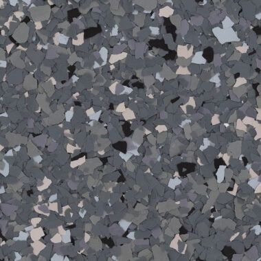 A close-up of grey-toned decorative floor flakes in black, charcoal, light grey, and white.