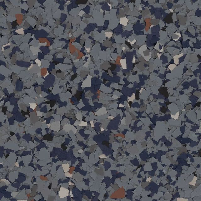 A close-up of dark grey, navy blue, white, and tan speckled vinyl decorative flakes for epoxy flooring.