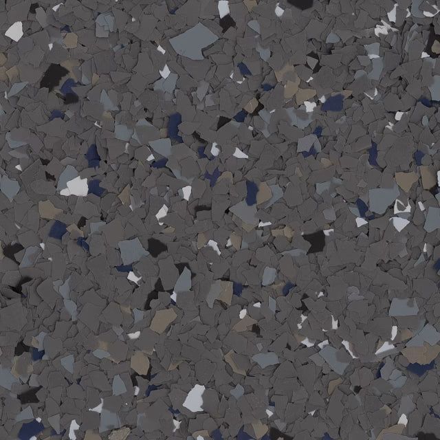 A close-up of dark grey epoxy flooring flecked with white, light grey, black, and blue vinyl color chips.
