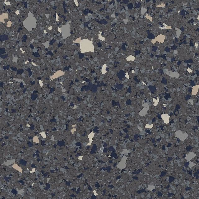 Dark gray flooring material with a speckled, multi-colored pattern of small tan, blue, and light gray vinyl chips.