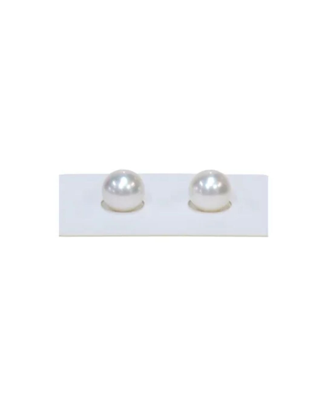 Two round, white pearl stud earrings resting on a white display card.