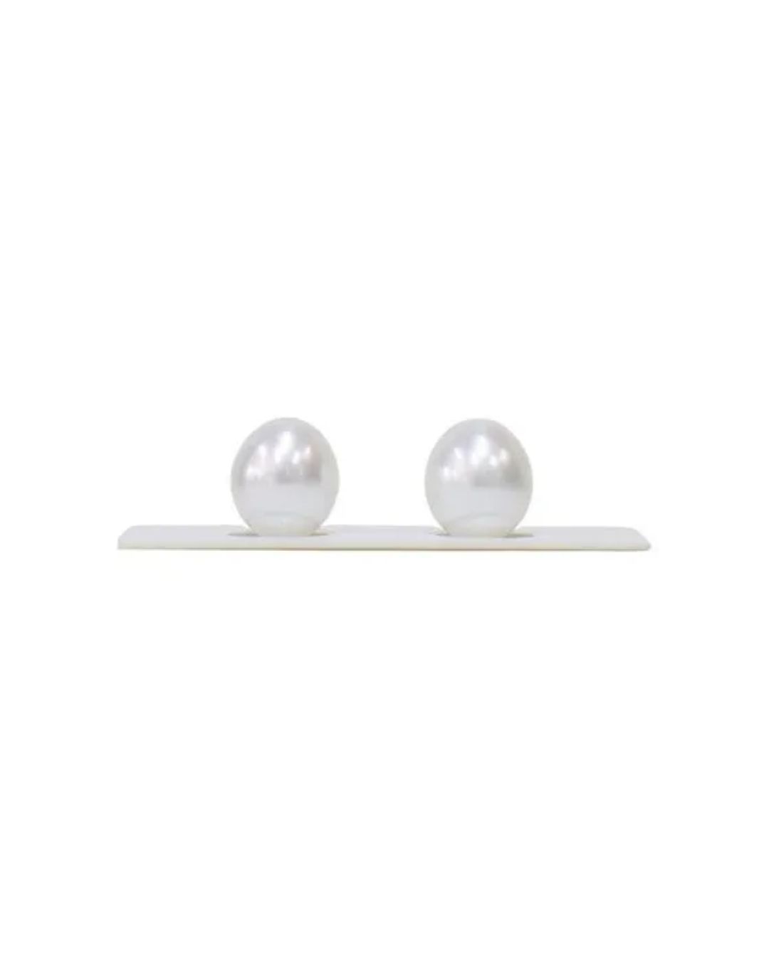 Two smooth, iridescent white pearls placed side-by-side on a white display stand.