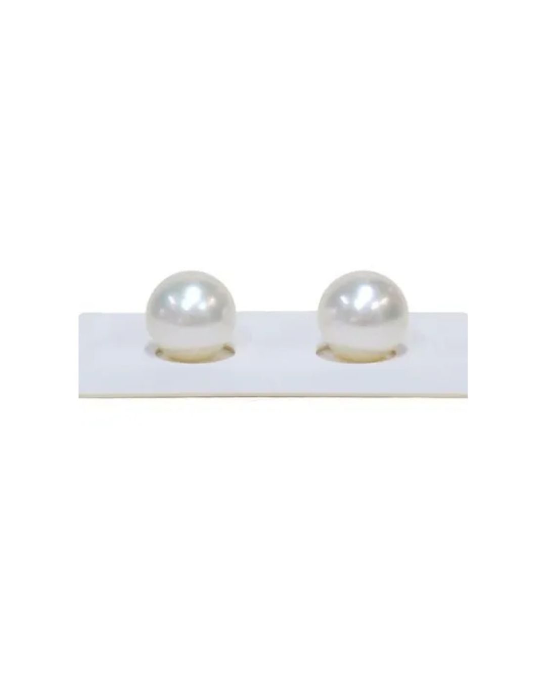 Two lustrous, round white pearls rest in circular cutouts on a rectangular white display card.
