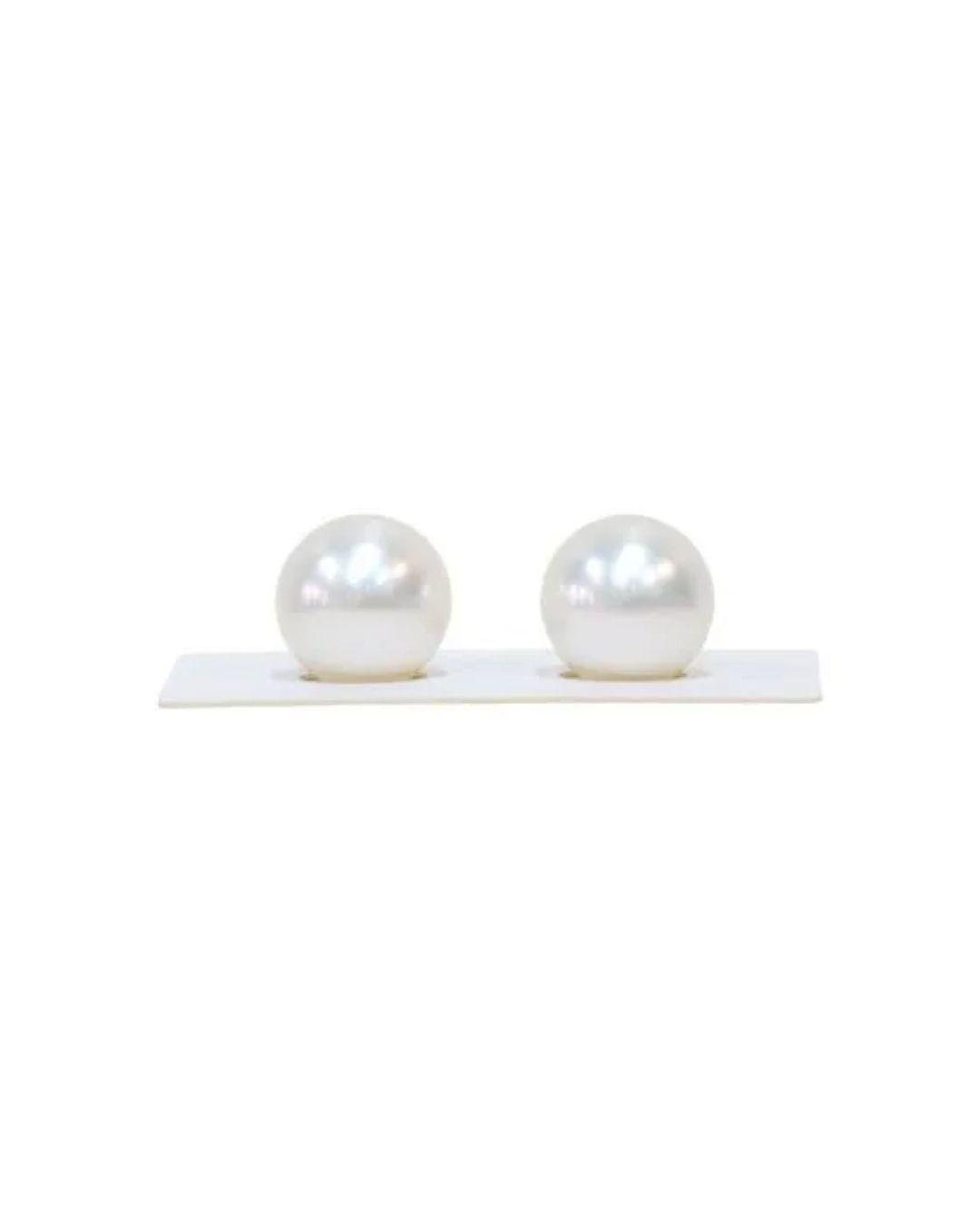 Two round, lustrous white pearls resting on a small white display stand against a white background.