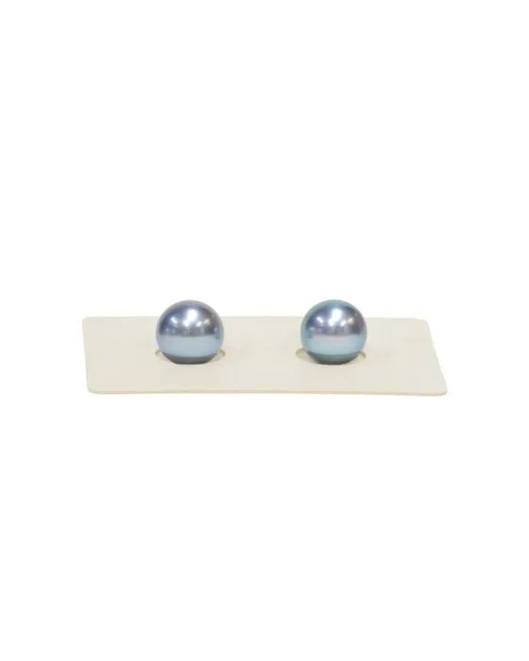 Two lustrous, metallic blue pearl spheres centered on a rectangular white display card.
