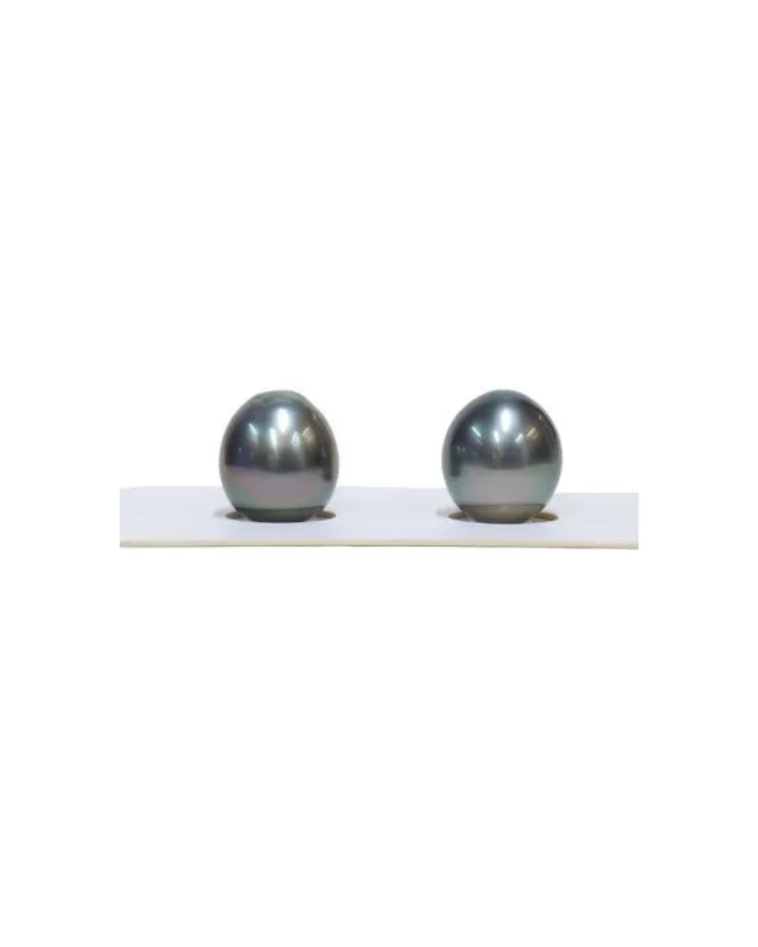 Two dark, lustrous, iridescent pearls are set side by side on a thin white rectangular display stand.