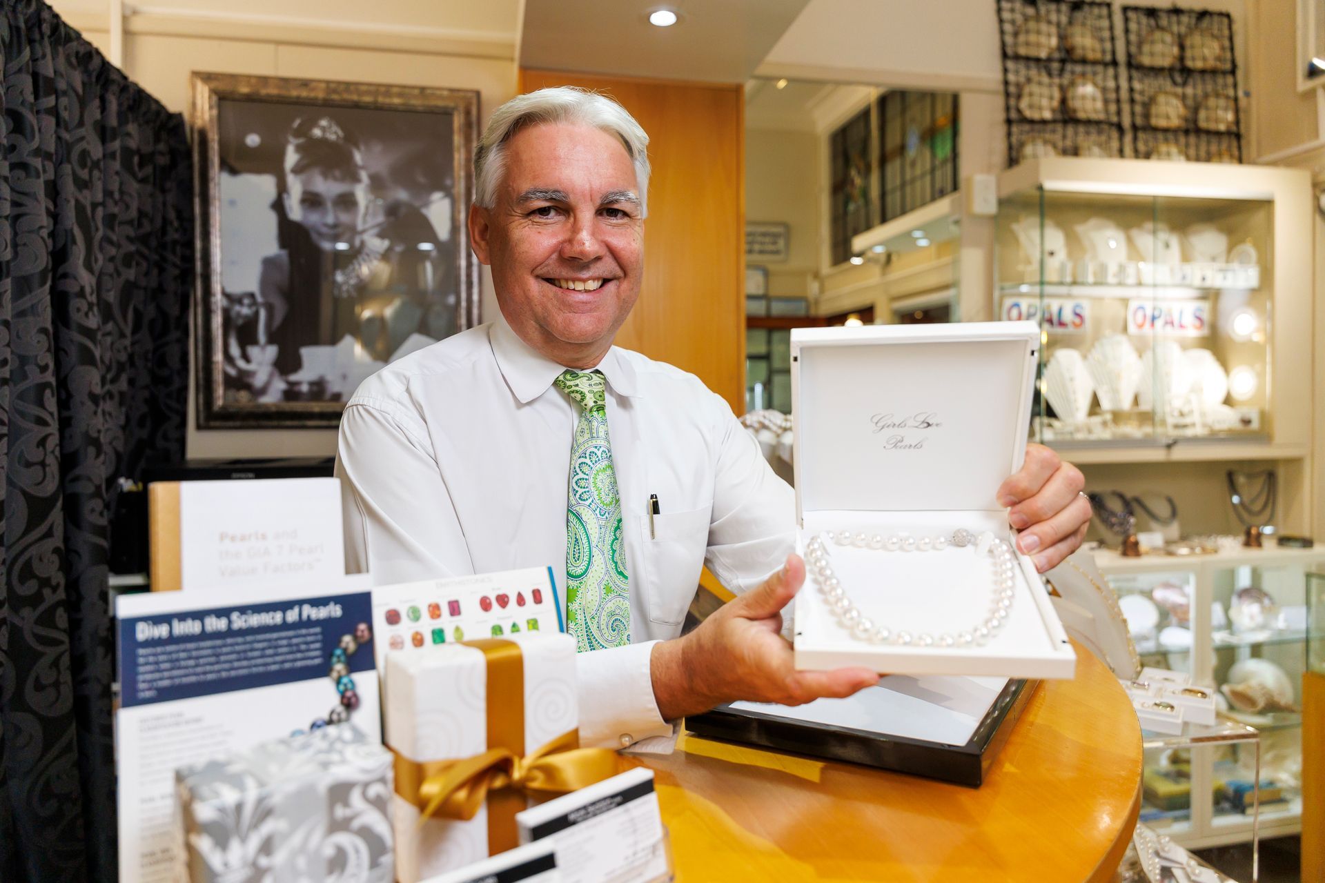 Jewellery expert showcasing custom pearl necklace over counter in Brisbane shop