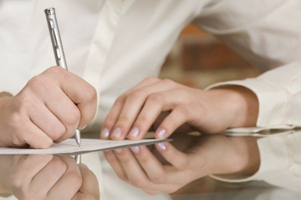 a person is writing on a piece of paper with a pen