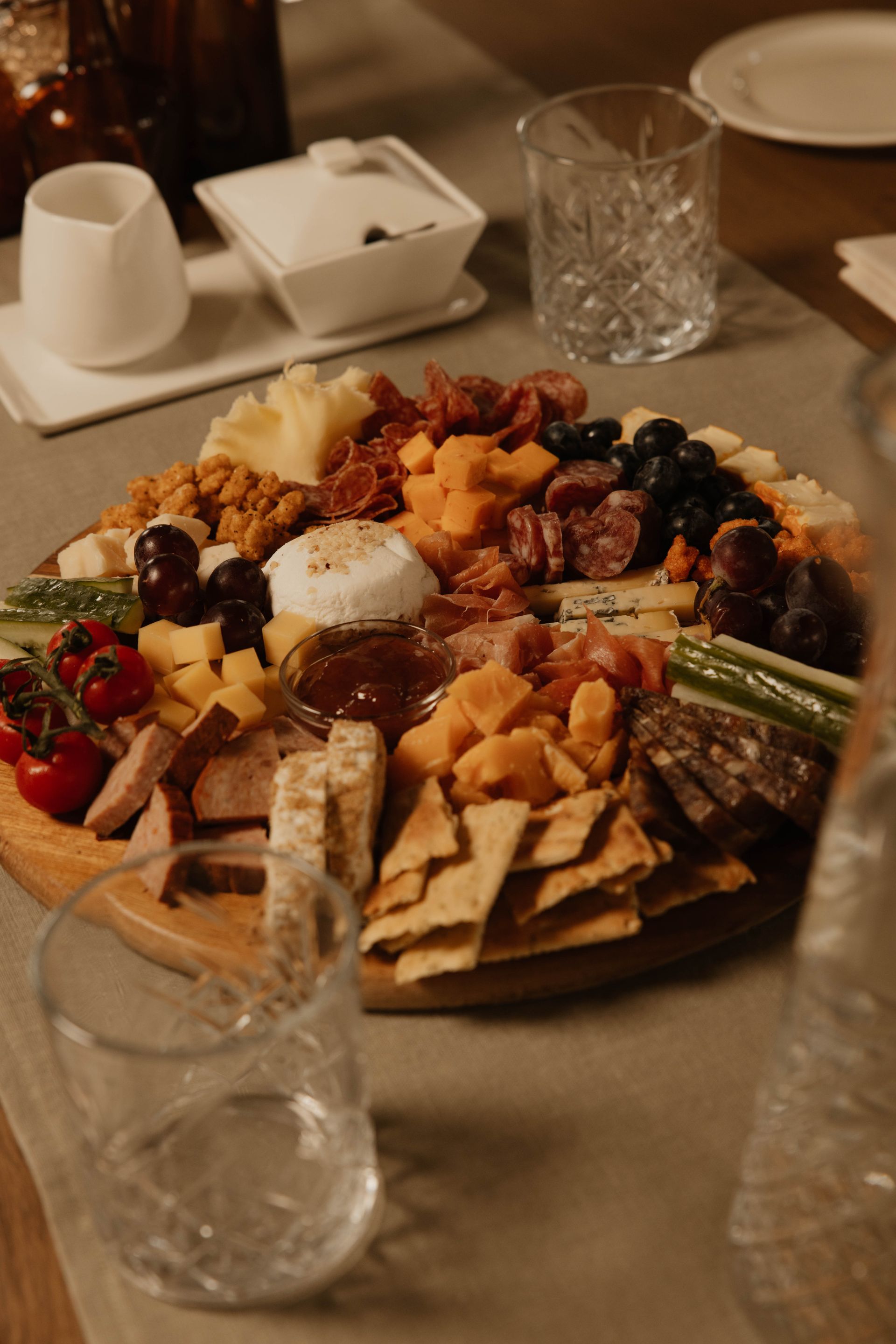 Een charcuterieplank met kazen, crackers, fruit en noten op een restauranttafel.