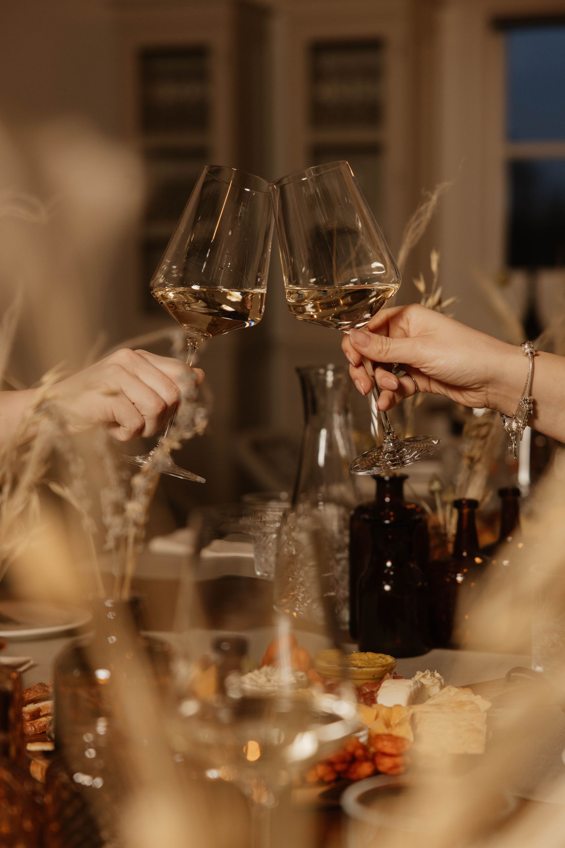 Mensen heffen het glas met wijn aan een sfeervol verlichte eettafel.