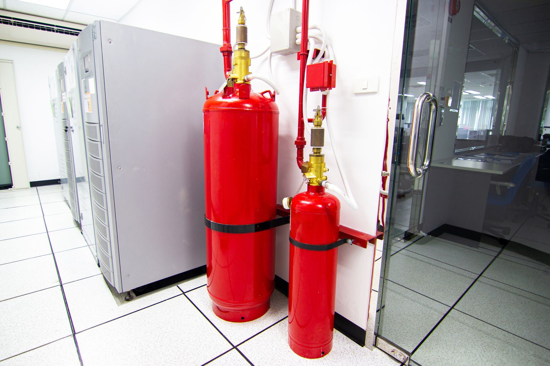 Two red fire extinguishers are sitting next to each other in a room. Two red fire extinguishers are sitting next to each other in a room.